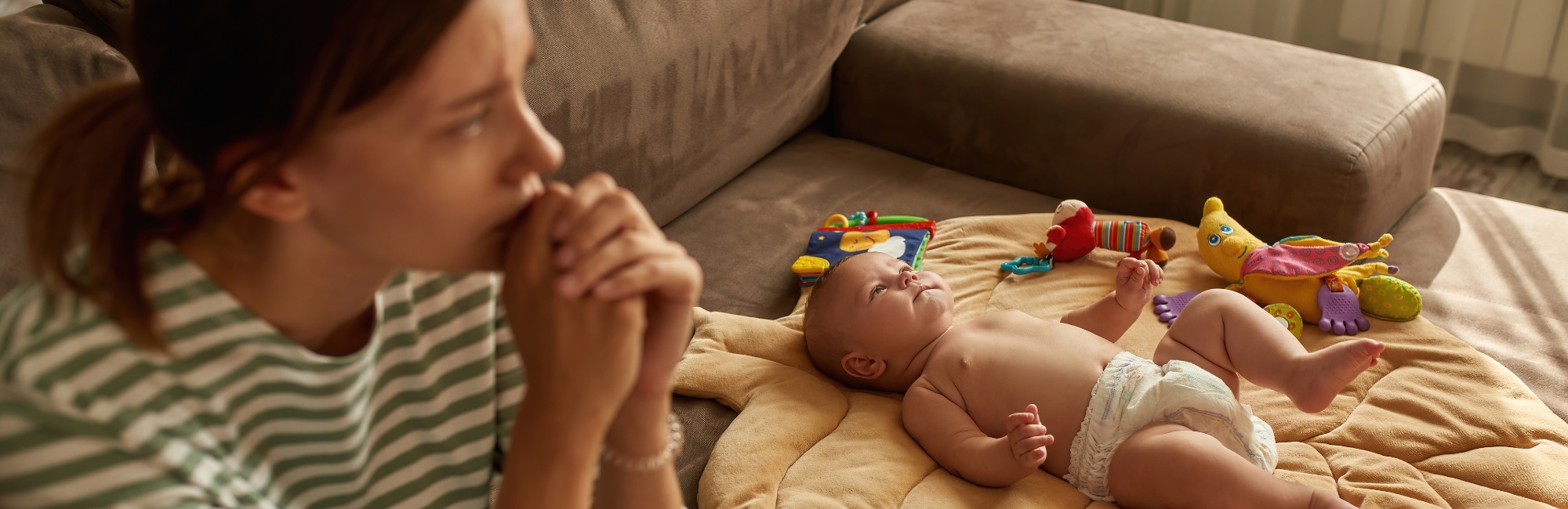 stressed and tired woman sits next to baby