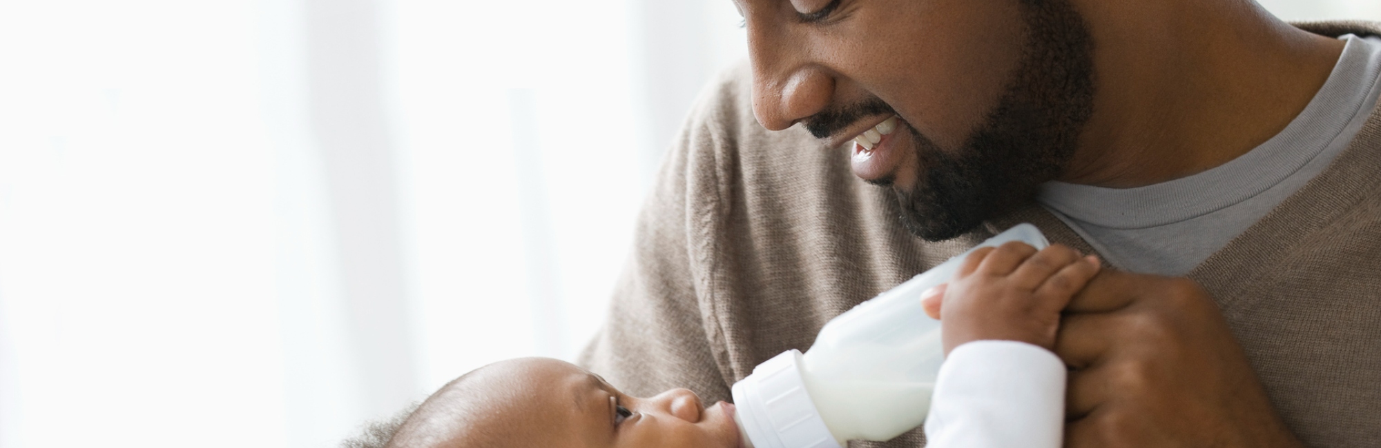 father looks lovingly toward their child held in their hands