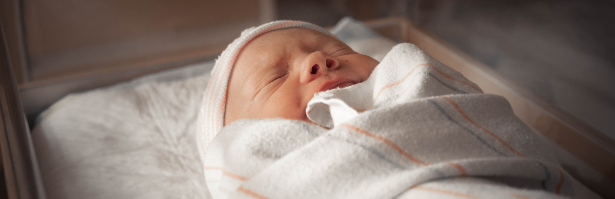 a swaddled baby asleep in a cot