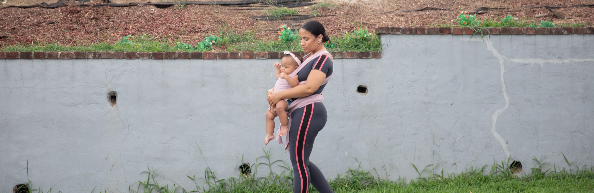 mother walks outside with baby in forward facing carrier
