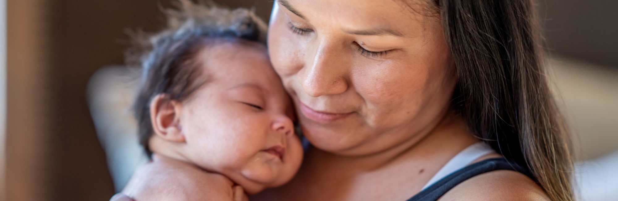 first nations american woman gently holds child