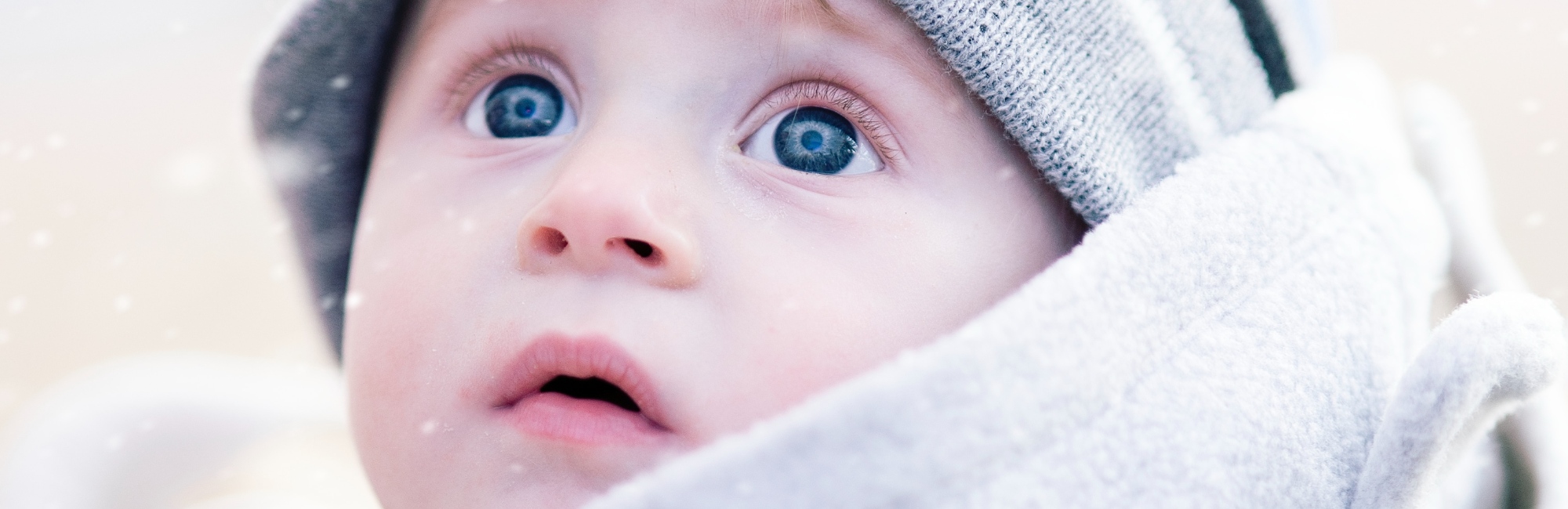 blue eyed baby wearing winter clothes outside in snow