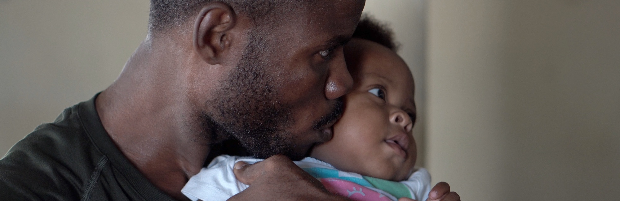 father kisses baby daughter on cheek