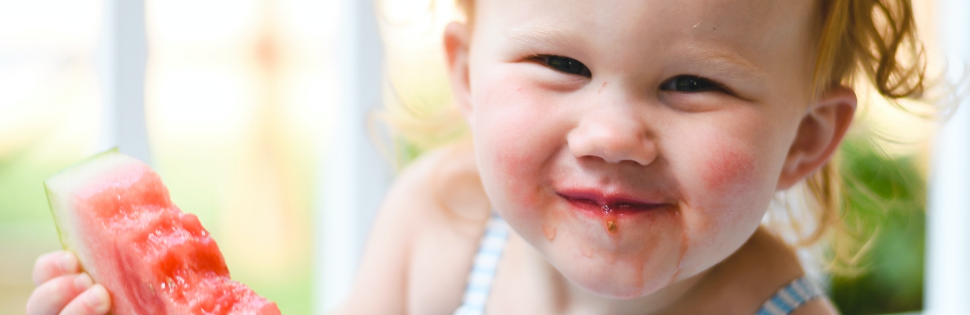 toddler eating watermelon happily