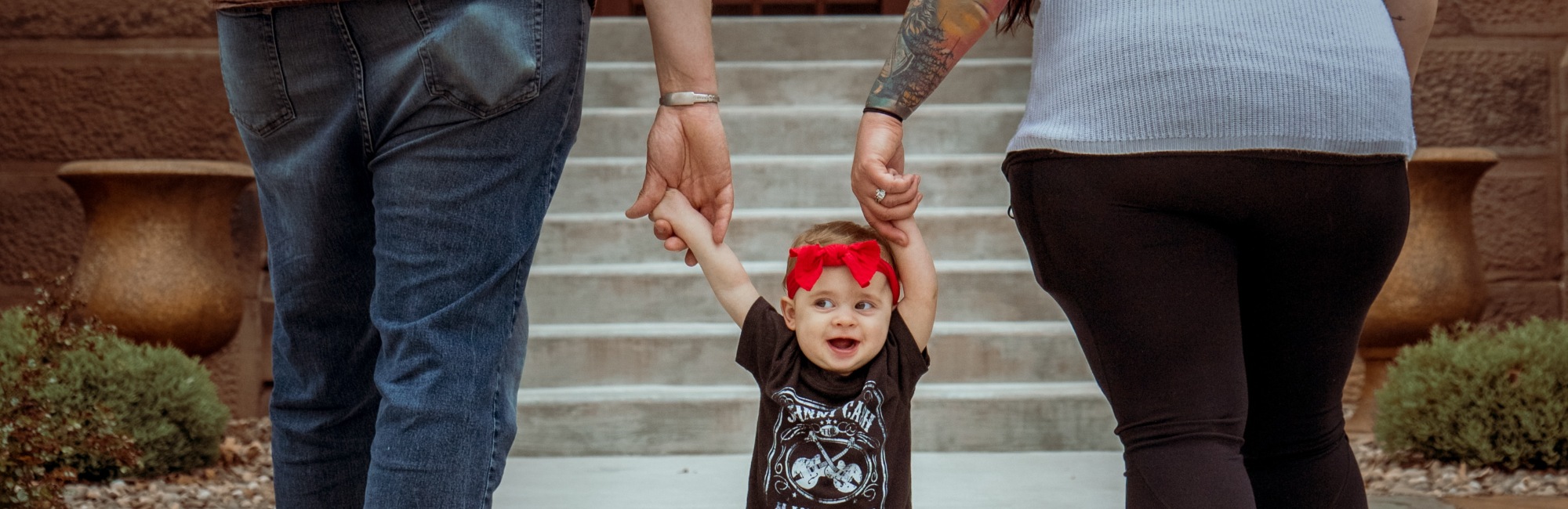 mum and dad walk while holding one of each of their toddler's hands