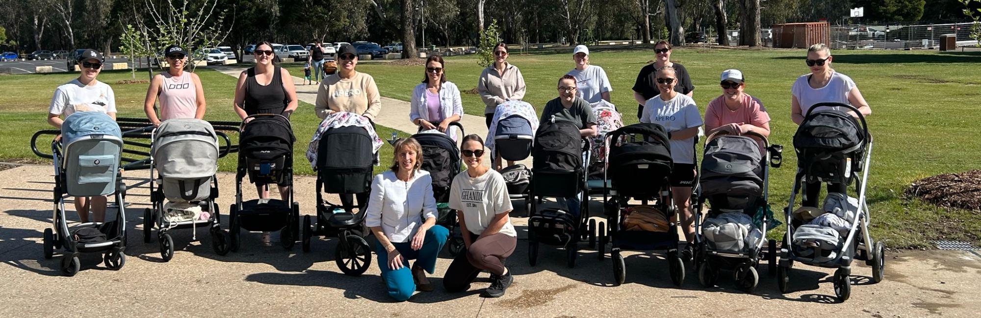 group of parents with their babies in prams pose for a photo outside with dr pam