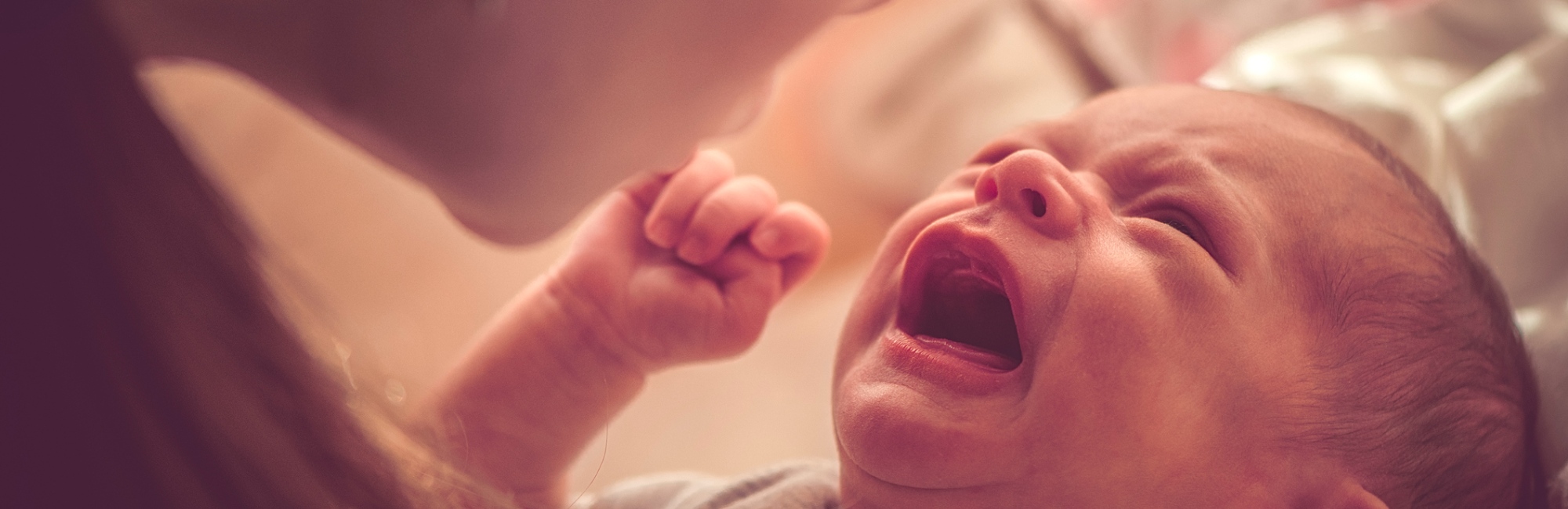 mother holds up crying baby