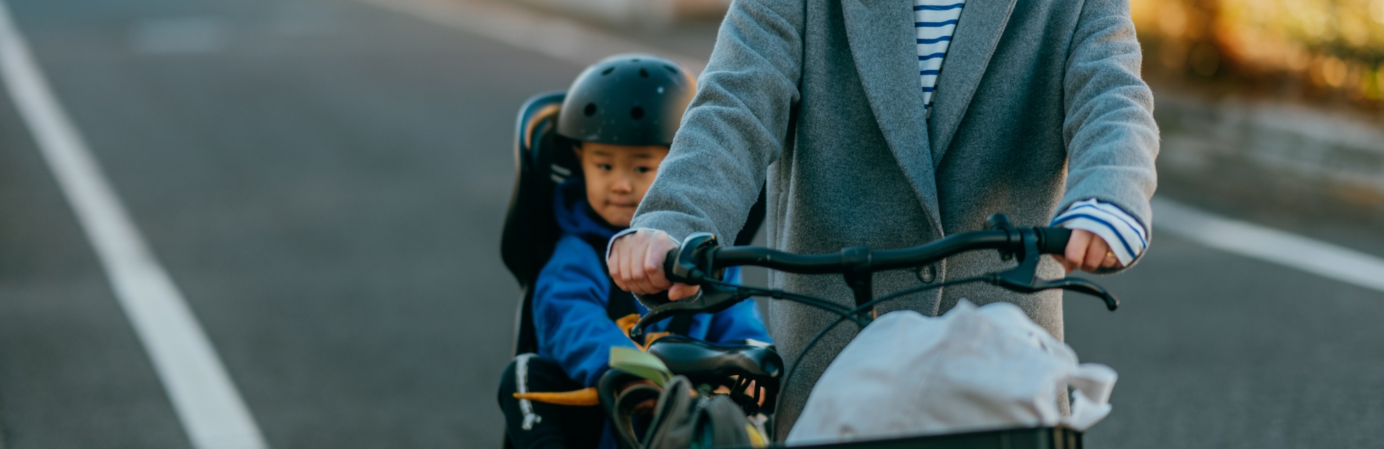 parent riding bike with sidecar containing toddler outside