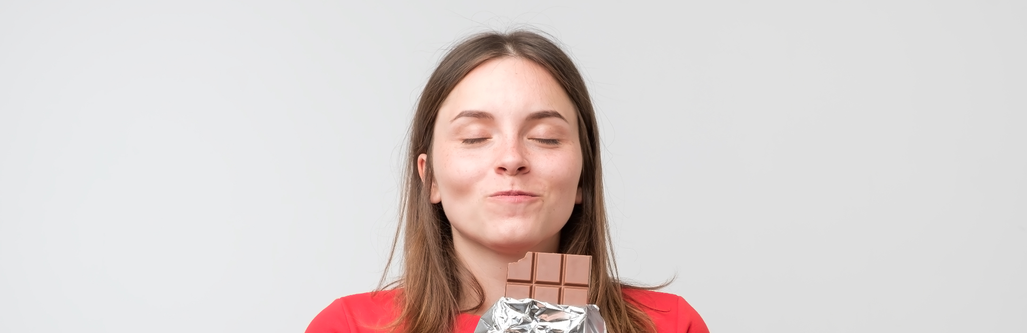 young caucasian woman happily eating chocolate