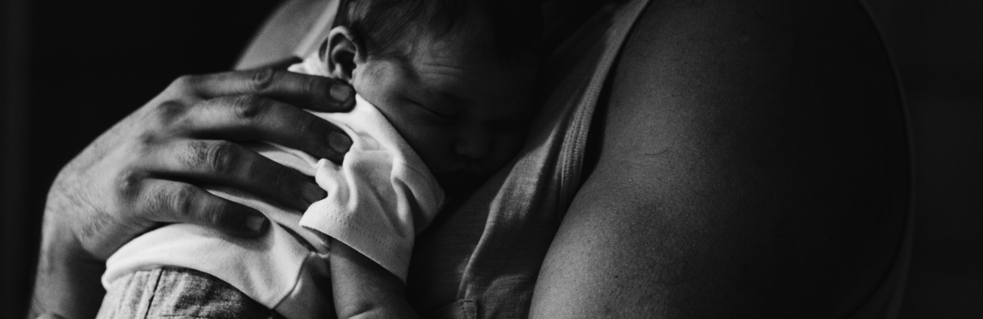 black and white image of parent cuddling baby to their chest