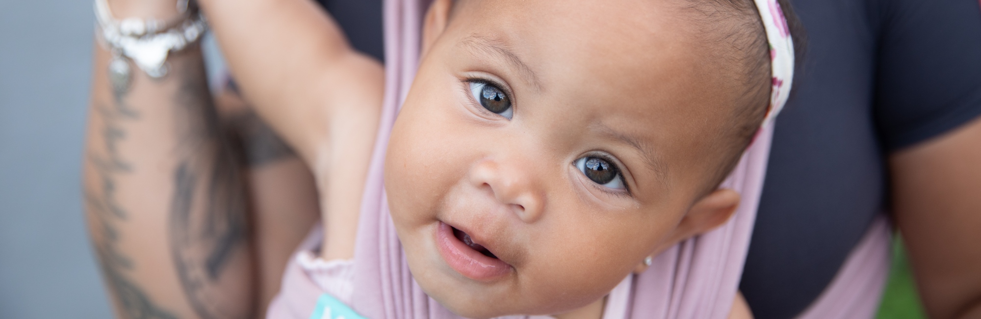 brown eyed baby in pink carrier