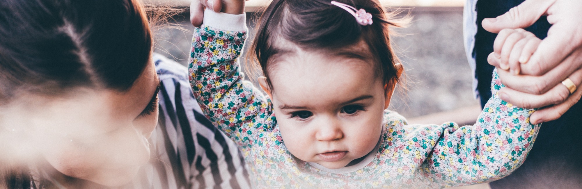 toddler holding hands outside with parents
