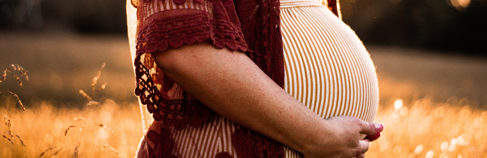 pregnant woman standing in field of grass